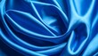 © Zajan - Close-up of intensely blue, smooth fabric with flowing folds. The sheen reflects light, highlighting the curves and textures