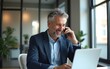 © lin - Smiling mature business man talking on cell phone using laptop in modern office. Mid aged businessman calling on mobile looking at computer having conversation on digital investment at desk.