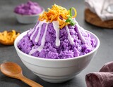 Bowl of purple yam dessert topped with white sauce and fried toppings, with a wooden spoon on a textured surface