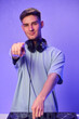 © Евгений Вершинин - Young DJ with headphones, Skilled DJ engaging with equipment in lively environment, Energetic DJ prepping for live performance amid colorful lighting and fashionable attire