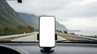 © Arsal Stock - Smartphone with a blank white screen mounted in a car on a scenic road trip with mountains and a cloudy sky providing navigation or entertainment on the journey