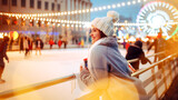A woman smiles while leaning on the railing of an ice skating rink surrounded by twinkling lights. Skaters glide in the background on a chilly winter evening.