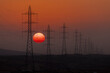 © Travel 'n' Lifestyle - View of stark power lines cutting across the horizon as the sun sinks, painting the sky with fire, contrasting industrial presence with natural beauty, Rub' al-Khali, United Arab Emirates.