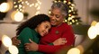 © SimpleDesignStudio - Loving African American grandmother and granddaughter sharing a warm hug at home during the festive Christmas season with blurred lights