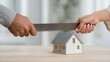 © StockHero - Hands of two individuals, one holding a saw, are dividing a miniature house on a wooden table, symbolizing the concept of divorce and asset division in a relationship