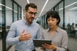 © diproduction - Business professionals discussing project on digital tablet in modern office hallway with glass walls and teamwork collaboration concept background. Ai generative