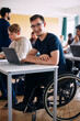 © Maskot - Portrait of physically disabled happy young man sitting with laptop at desk in high school classroom