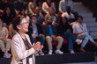 © Maskot - Happy mature female presenter at seminar in theater