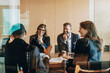 © Maskot - Smiling male and female business professionals sitting with colleagues in meeting room at law office seen from glass