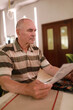 © Arkady Chubykin - Elderly man reading a menu in a cozy restaurant during lunchtime with warm lighting
