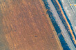 © UrbanWitness - Abstract aerial view showcasing stark division between vibrant brown agricultural field and contaminated industrial area. Polluted channel and toxic gray sludge highlight severe environmental damage