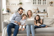 © fizkes - Joyful laughing couple with small children watching videos on notebook