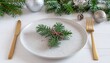 © sanjayart - Elegant Christmas Place Setting with Gold Cutlery Ready for a Festive Holiday Feast, Sparkly Ornaments and Evergreen Boughs Add Cheer
