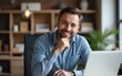© li - Thoughtful smiling male professional sitting with hand on chin in home office. High quality