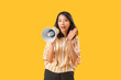 © Pixel-Shot - Beautiful Asian woman shouting into megaphone on yellow background. Dialogue concept