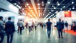 © mila103 - Attendees walk through a vibrant exhibition hall featuring many booths and displays at a large industry event showcasing products and networking opportunities.