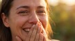 © Mikus - Woman smiling with hands covering mouth in bright sunlight, tears of joy on cheeks