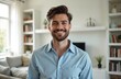 © Vadym - Handsome man smiles in bright home interior. Happy homeowner or freelancer poses. Millennial guy in light blue shirt looking at camera indoors.