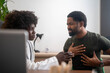 © Nenad - Black man complaining of chest pain while female doctor examines him in clinic