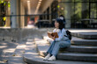 © Apichat - Asian student woman reading book on university campus stairs