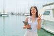 © luismolinero - Young pretty Ukrainian woman holding a tablet at outdoors smiling and showing victory sign