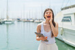 © luismolinero - Young pretty Ukrainian woman holding a tablet at outdoors shouting with mouth wide open
