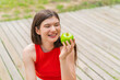 © luismolinero - Young pretty woman at outdoors holding an apple with happy expression