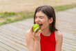 © luismolinero - Young pretty woman at outdoors eating an apple