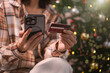 © NaMong Productions - woman using Mobile holiday shopping payment person holding smartphone and credit card to complete secure online transactions during festive Christmas season