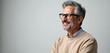 © Vadym - Handsome middle aged man with glasses smiles. The man in beige sweater has a gray beard and stylish haircut. Senior model shows happiness and confidence on white background.