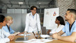 © Prostock-studio - Smiling man chief physician making presentation in front of his male and female international colleagues during morning brainstorming at clinic, panorama. Medical conference, training concept