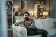 © Dusan - Happy bearded man relaxing on living room couch