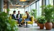 © Pete - Colleagues in a bright, modern office common area. People sit on yellow sofa near potted plants. They talk and look at tablet device in office lounge.