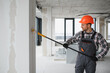 © Serhii - Construction worker painting walls with roller in building renovation