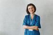 © shurkin_son - Successful confident Caucasian female massage therapist or kinesiotherapist posing against grey studio background with copy space for your advertising content in blue uniform standing with folded arms