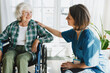 © shurkin_son - Side view of friendly caregiver or nurse in blue uniform getting acquainted with patient in wheelchair newly arrived at hospital or geriatric clinic for rehabilitation treatment after brain stroke