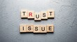 © Stocker Man - Wooden letter tiles spelling out trust issue on a textured gray concrete background, symbolizing relationship problem