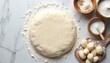 © Viktor - Raw pizza dough on white marble table surrounded by flour. Dough is round and flat. Three wooden bowls with flour and small dough balls. Baking ingredients for homemade pizza preparation.