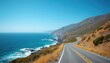 © Viktor - Winding road along ocean coast with blue water, mountains. Road curves along shoreline with waves. Yellow line on asphalt road. Brown grass, green bushes on side. Clear blue sky. Ocean beach road