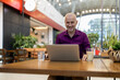 © Jelena - Smiling man working on laptop in modern workspace