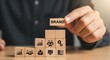 © Aftarun - Businessman holding a wooden block with the word brand on top of a growth chart made of blocks, symbolizing brand building and success