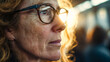 © ABF_MATEO - Close-up of a thoughtful woman with freckles, wearing glasses, gazing off into the sunlight with a serene expression on her face.
