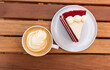 © Guillermo - Composición plana (flat lay) de desayuno o merienda con taza de café latte y rebanada de pastel Red Velvet sobre mesa de madera. Estilo blog gastronómico.