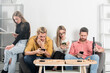 © Volodymyr - Friends sit together but all look at their phones. Group friends with social media concept. Group of people disconnected. Digital addiction in daily life. Everyone absorbed in devices.