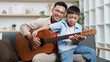 © itchaznong - Family Life: Father and son enjoying music together with a guitar