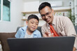 © itchaznong - Family Life: Father and son enjoying quality time together while using a laptop