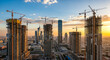 © Celt Studio - Panoramic view of city construction site with cranes building new skyscrapers at sunset urban development real estate investment architecture growth industry