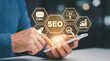 © Yudi - Man Using Smartphone with Glowing Seo Concept Icons for Digital Marketing