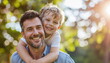 © Phanupong - Father and son smiling outdoors happy boy hugging dad's neck summer sunshine