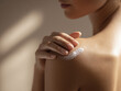 © Yaroslav - Woman Applying Cream to Shoulder in Soft Sunlight